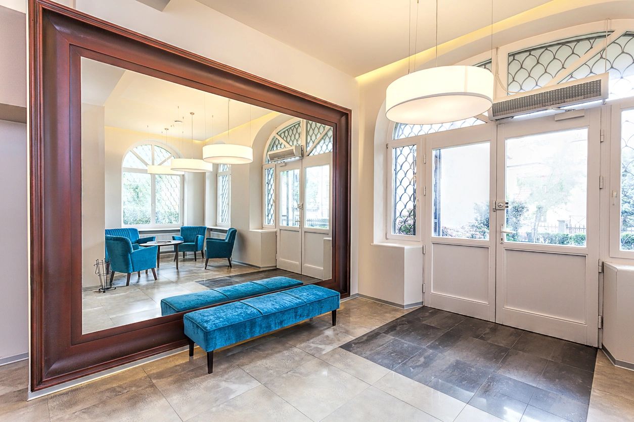 An Elegant foyer with a large mirror and luxury sofa.